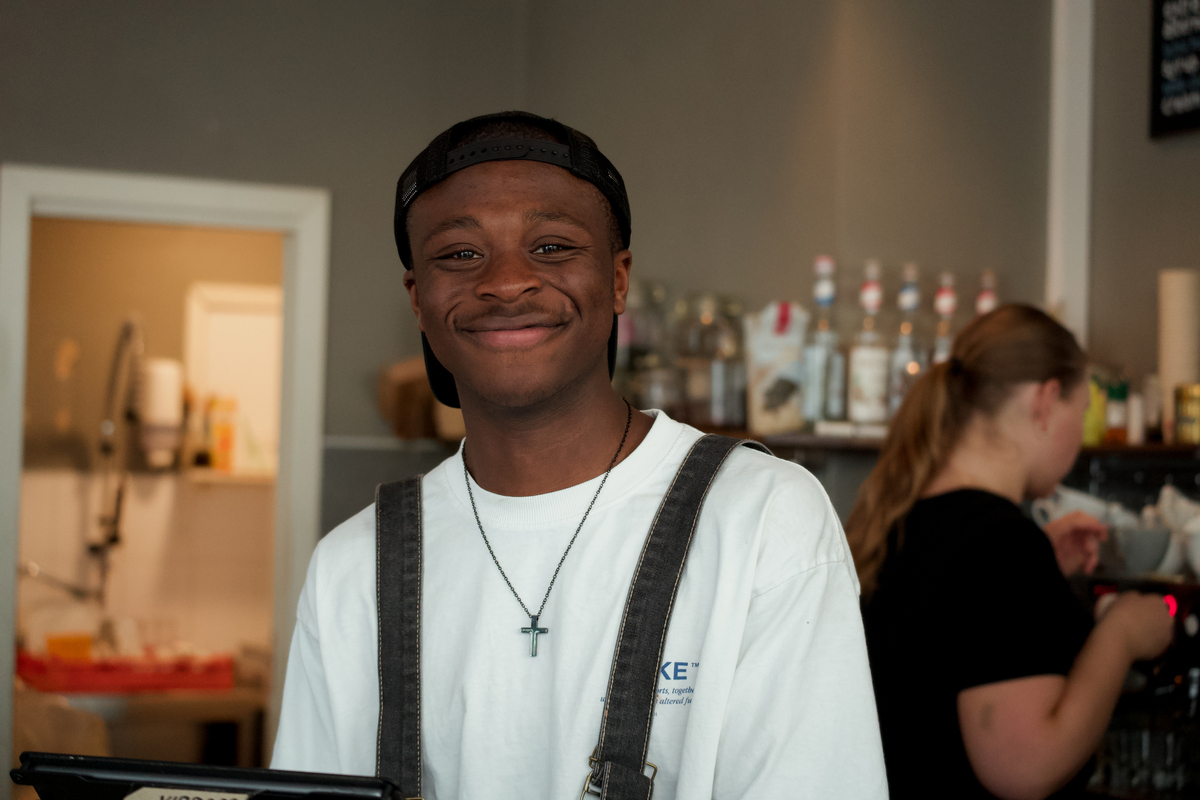 Smilende mann som jobber på cafe