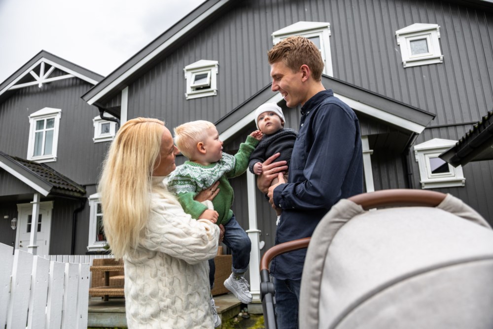 Mor far og to barn står utenfor et hus