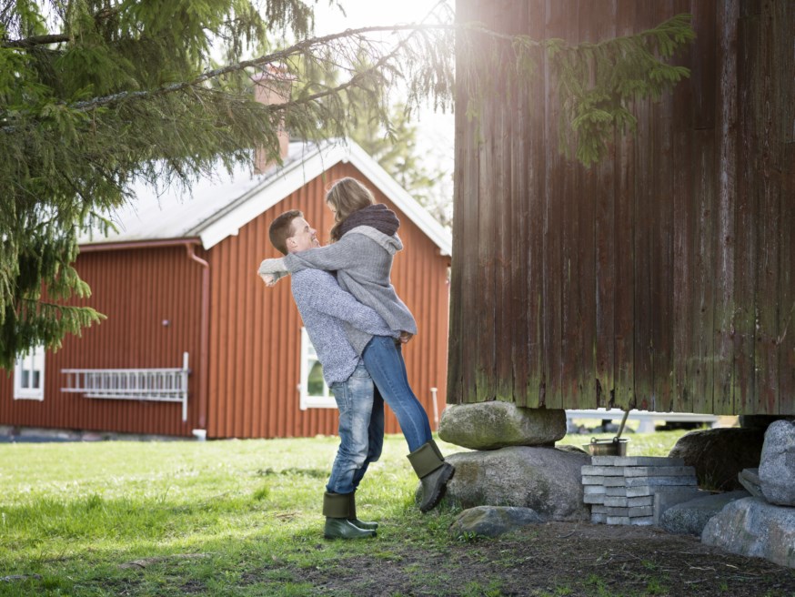 Ungt par som omfavner hverandre på gårdstunet